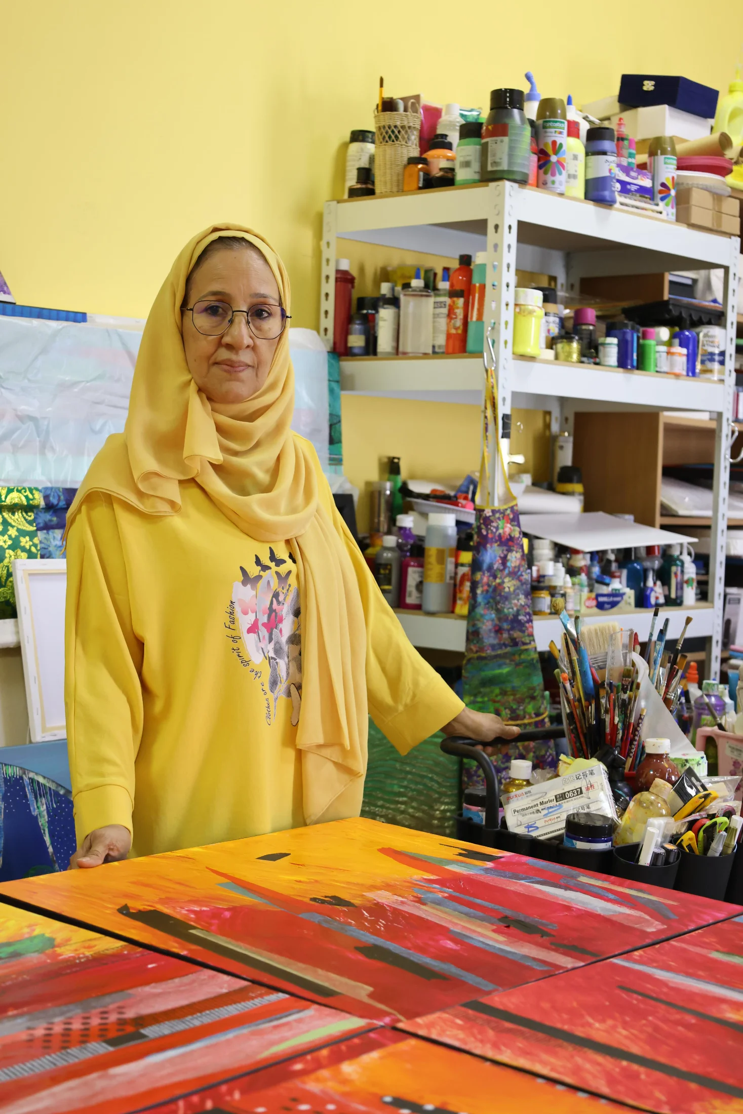 Dr. Najat Makki in her studio surrounded by her pigments, tools, and ongoing works. Photo courtesy of the artist.